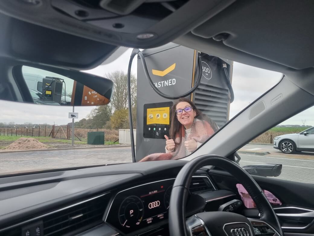 Suzie gives two thumbs up to the camera outside the Audi E-tron